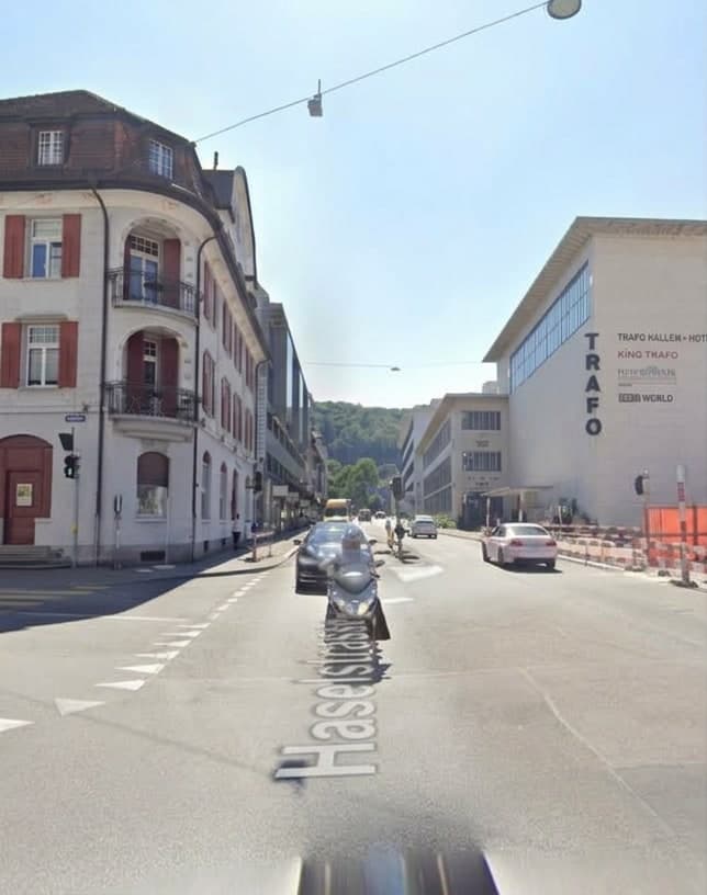 Blick die Haselstrasse hinunter beim Trafo: breite Fahrbahn, parkierte Fahrzeuge, keine Bäume